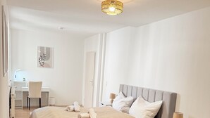 A modern bedroom with a large bed, bedside tables, a desk, and a chair. - DREAMZzz AltstadtTraum in the heart of Coburg|Parking lot (Coburg)