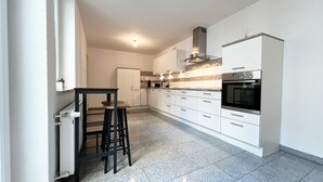 A modern kitchen with white cabinets, a built-in oven, and a countertop with a coffee maker. - DREAMZzz AltstadtTraum in the heart of Coburg|Parking lot (Coburg)