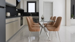 A modern kitchen with a dining area, featuring a glass table, four chairs, and a black countertop. - 2 Chambres Spacieux a Dely Ibrahim (Algiers)