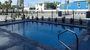 A swimming pool with a black metal fence, a lifeguard stand, and a sign indicating no diving. - Seabreeze Hotel, An Ascend Collection Hotel (Galveston)