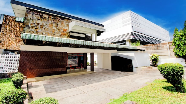 A modern two-story house with a stone facade, a flat roof, and a covered patio area. - Hotel O Hotel Wisma Hasanah (Semarang)