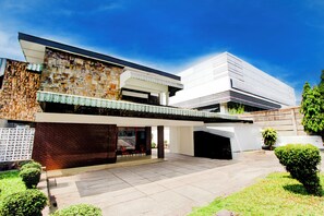 A modern two-story house with a stone facade, a flat roof, and a covered patio area. - Hotel O Hotel Wisma Hasanah (Semarang)