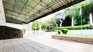 A covered outdoor area with stone walls and potted plants. - Hotel O Hotel Wisma Hasanah (Semarang)
