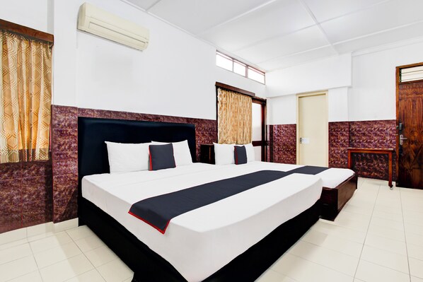 A hotel room with a large bed, a small bedside table, a wardrobe, and a window with curtains. - Hotel O Hotel Wisma Hasanah (Semarang)