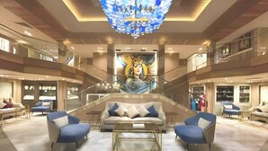 Eine großzügige Lobby mit einer zentralen Treppe, moderner Möblierung und einer großen Kronleuchter.