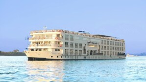 Ein großes, mehrstöckiges Flusskreuzfahrtschiff mit Balkonen und einem Rettungsboot auf dem Deck.