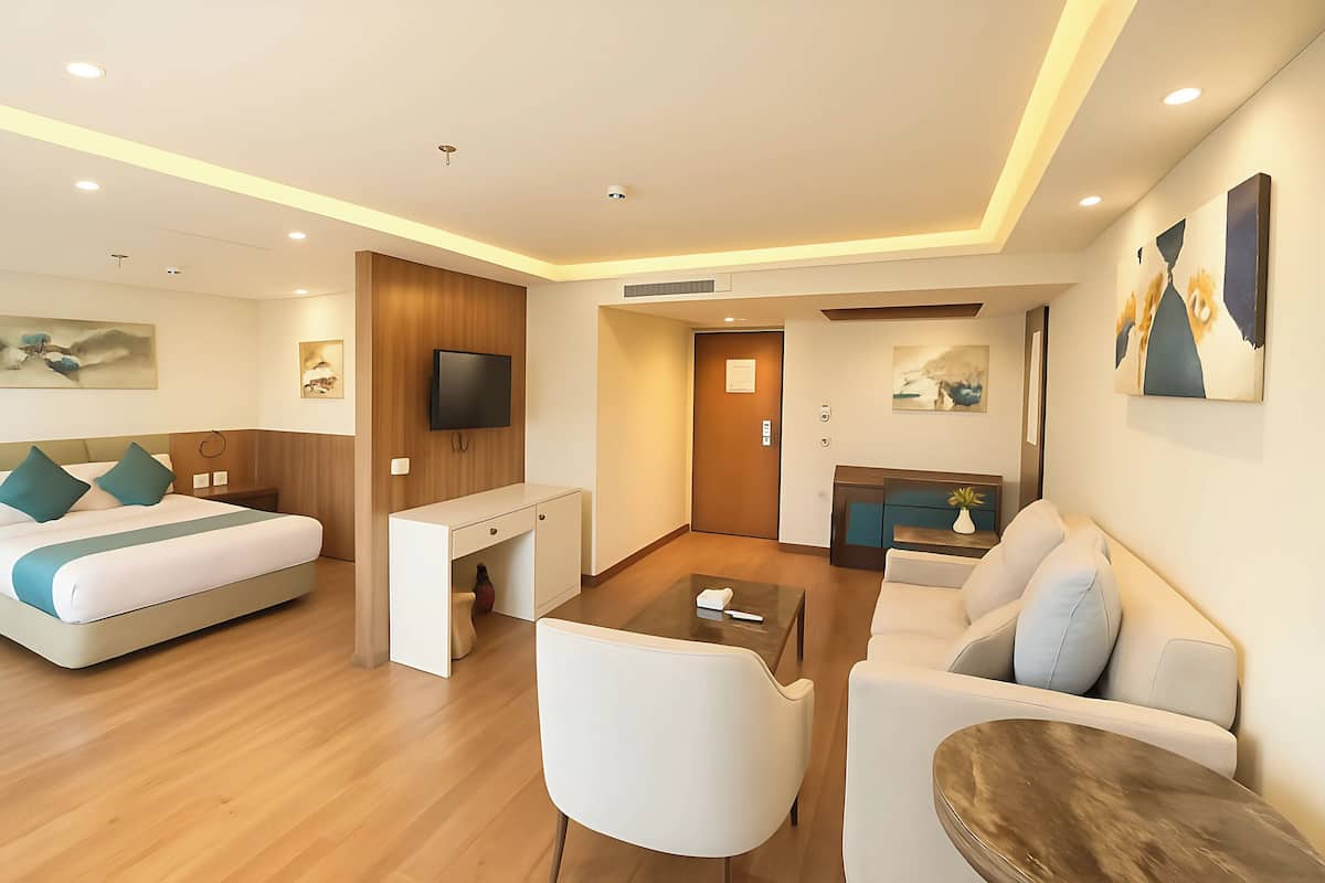 Ein modernes Hotelzimmer mit Bett, Schreibtisch, Sofa und Fernseher.