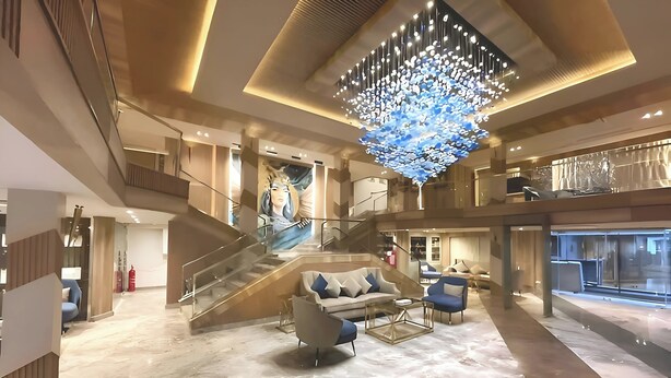 Eine geräumige Lobby mit einem prächtigen Chandelier, einer Treppe und einem großen Sofa.