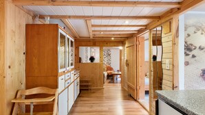A wooden interior with a kitchen area, wooden walls, and a hallway leading to a dining area. - Apartment 'Schwäblehof' (Triberg im Schwarzwald)