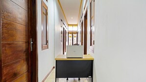Un couloir avec des portes en bois, un ordinateur portable posé sur une table et un sol carrelé.