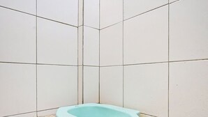 Une petite salle de bain fermée, avec une seule baignoire, des murs carrelés et un sol carrelé.