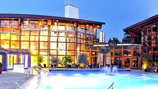 Un edificio moderno con piscina, mobiliario exterior y cielo despejado.