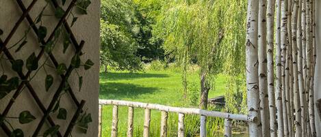 A balcony with a view of a lush green landscape, including a river and trees.