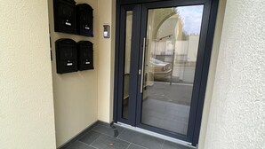 Ein Flur mit einer Glastür, die zu einem Parkplatz führt. Drei Briefkästen sind an der Wand angebracht.