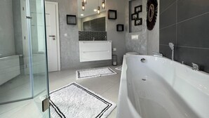 Ein modernes Badezimmer mit Duschkabine aus Glas, freistehender Badewanne und Waschtisch mit Spiegel und Waschbecken.