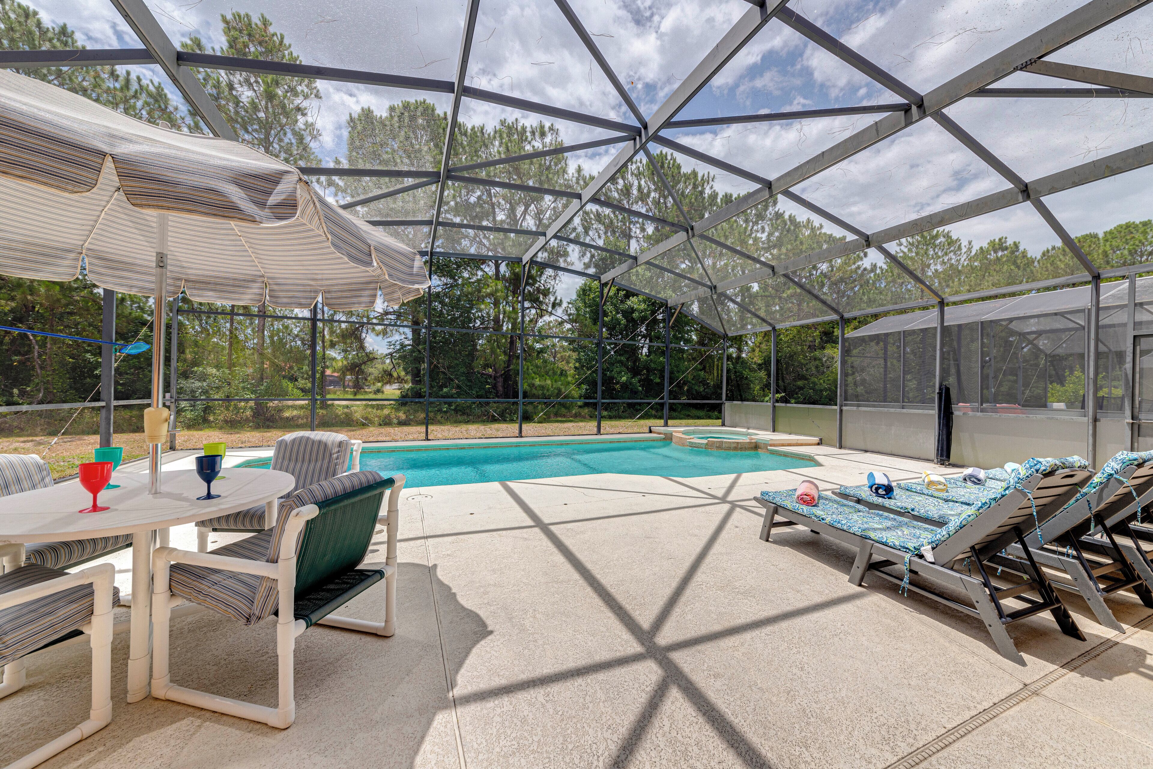 An outdoor pool area with lounge chairs, a table, and a covered seating area.
