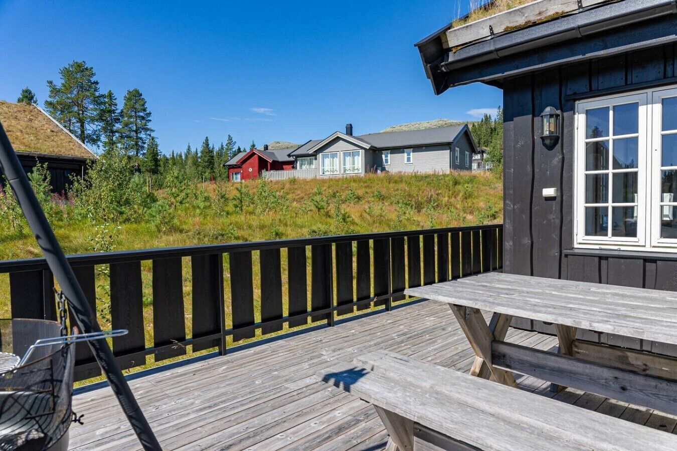 A wooden deck with a picnic table, a black railing, and houses in the background.