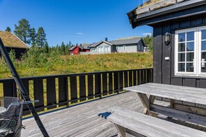 A wooden deck with a picnic table, a black railing, and houses in the background.