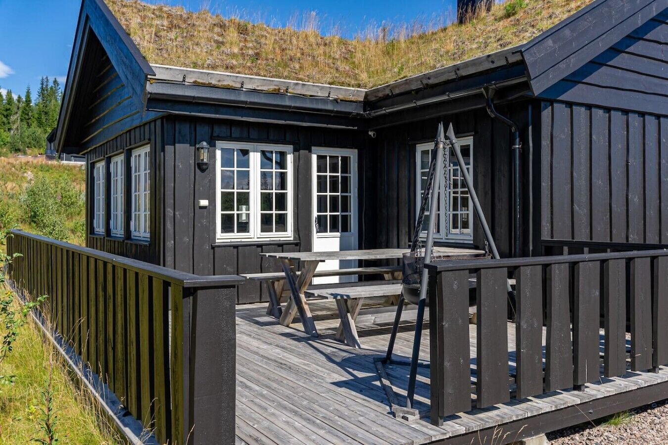 A wooden cabin with a deck, a swing, and a door.