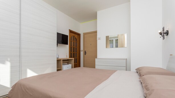 A bedroom with a bed, a wardrobe, a television, a mirror, and a desk. - Bed and Breakfast 'Sentiti A Casa' with Wi-Fi and Air Conditioning (Bronte)