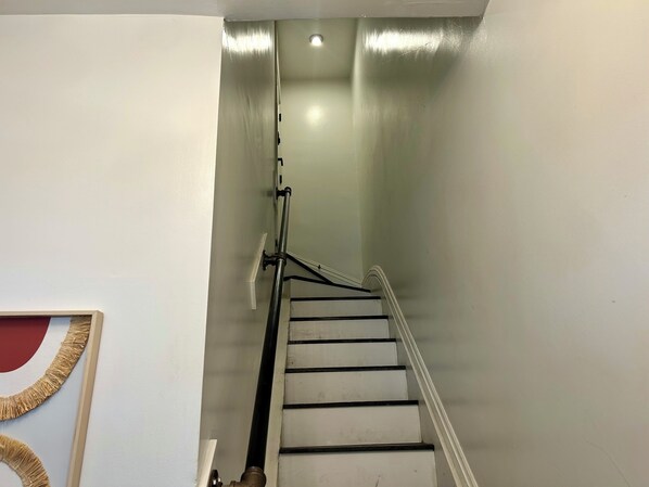 Eine Treppe mit Handlauf, eine Lampe am oberen Ende und ein gerahmtes Bild an der Wand.