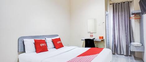 Una habitación de hotel con una cama, una mesita de noche, un aire acondicionado, un espejo y una cortina.