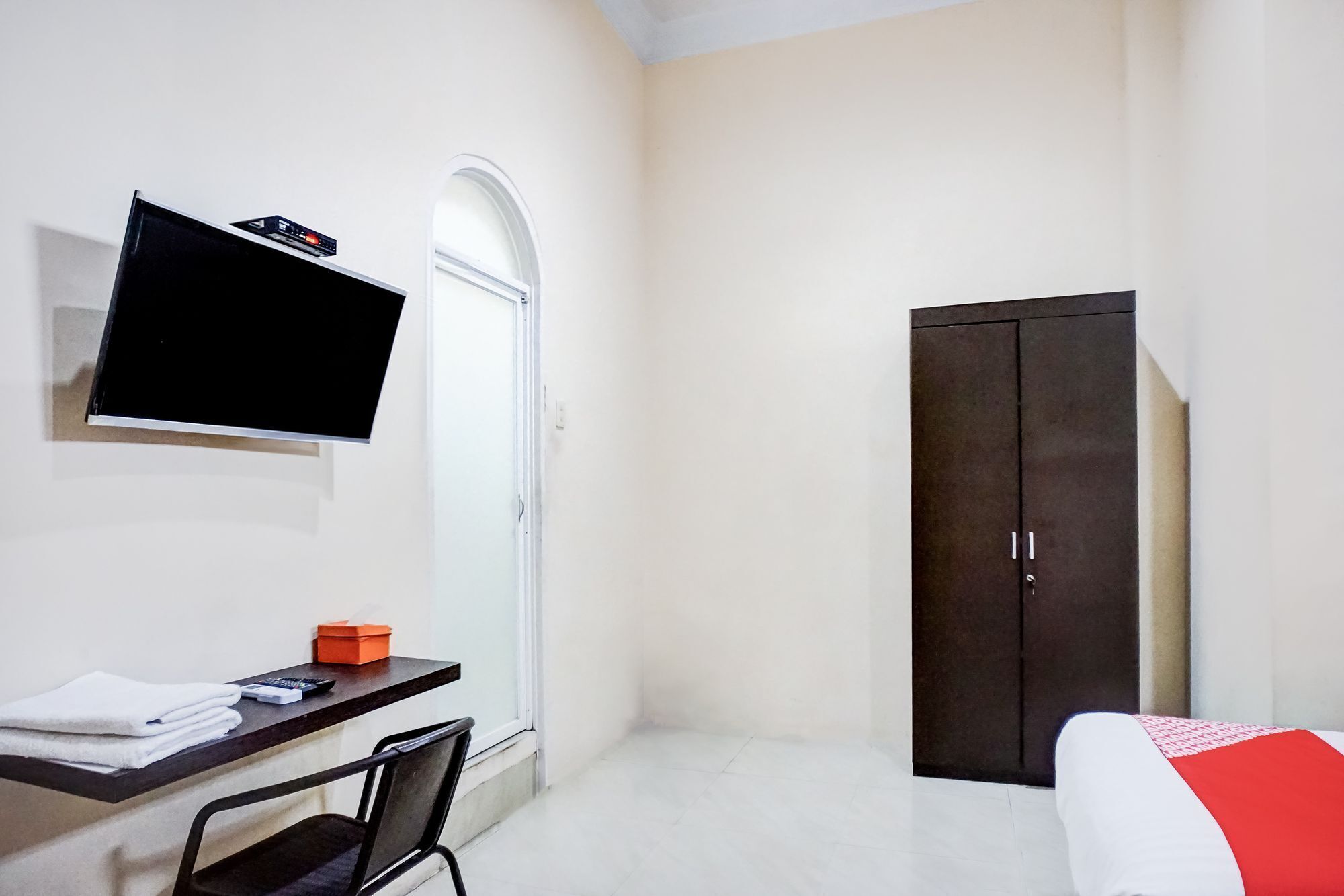 A room with a bed, a desk with a chair, a television, and a wardrobe.