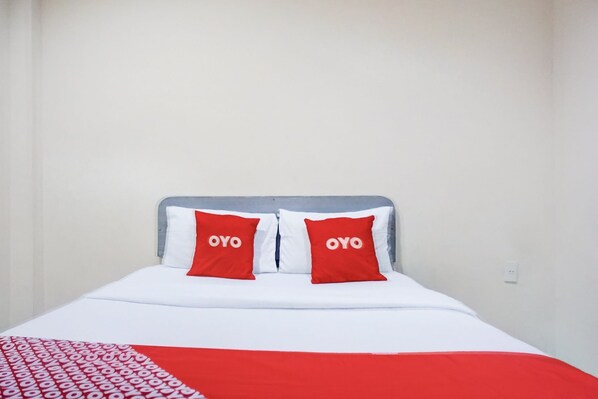 A bed with a white and red bedspread, two red pillows with the word "OYO" on them, and a grey headboard. - Dancenter Ralica Residence (Medan)
