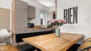 Et moderne køkken med et træbord, sorte stole og en vase med blomster.