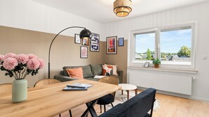 En moderne stue med et træspisebord, en sofa og et stort vindue med udsigt til det fri.