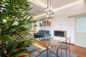 Una sala de estar moderna con una mesa de comedor de vidrio, un sofá azul y una planta grande en maceta.