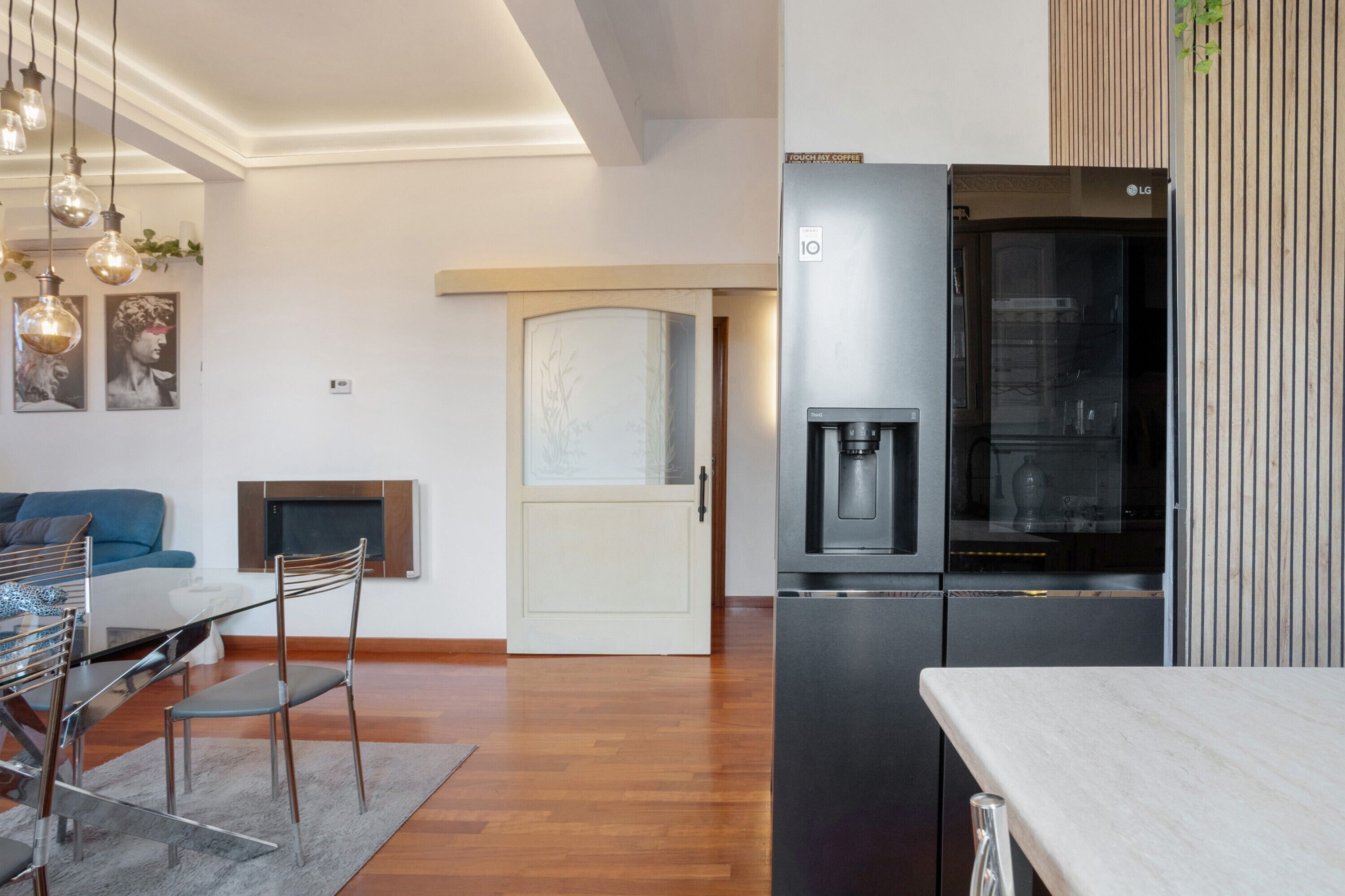 Een moderne keuken met een roestvrijstalen koelkast, een koffieapparaat en een eethoek met een tafel en stoelen.