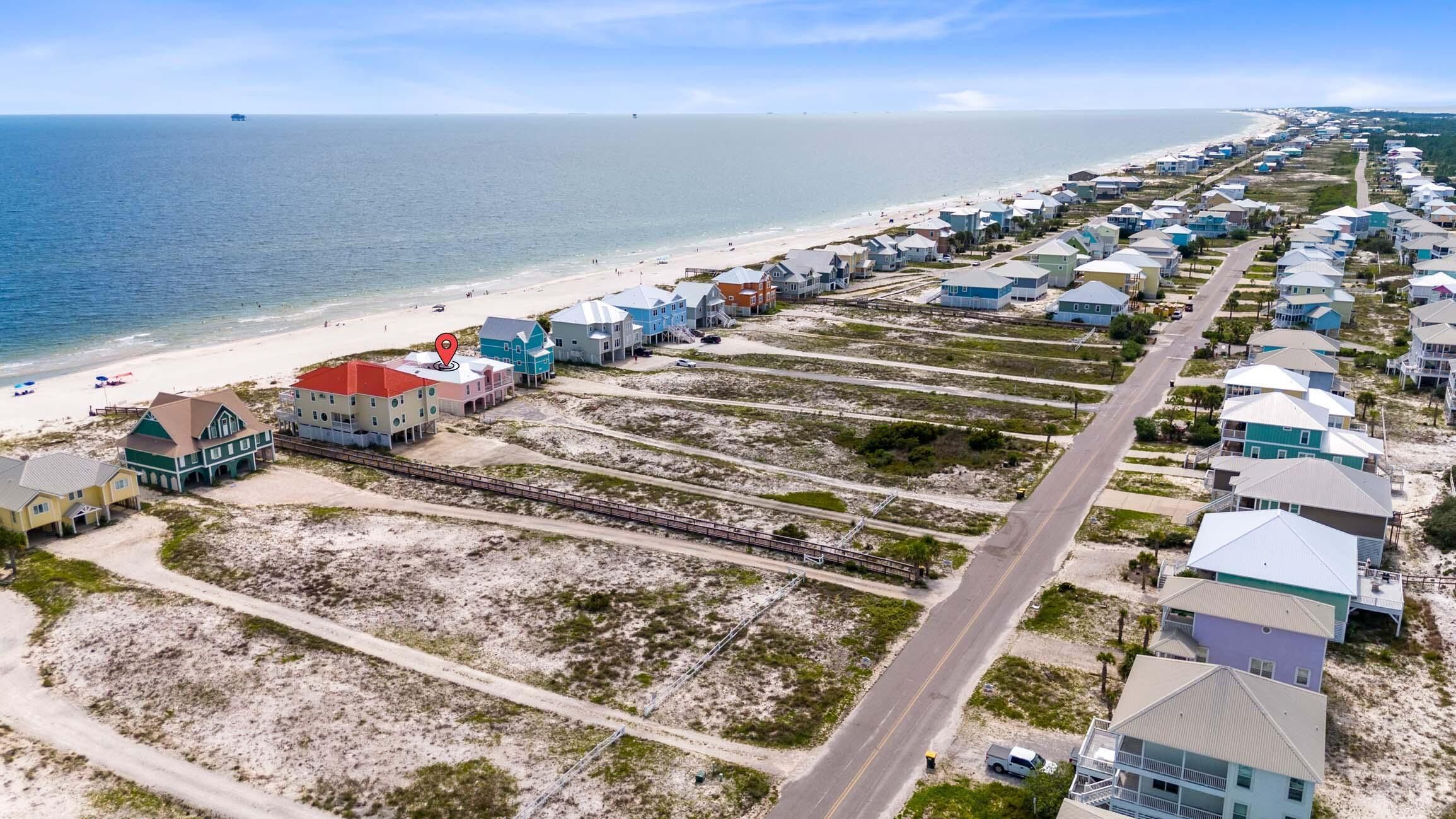 Een overzicht vanuit de lucht van een kustgebied met woonhuizen, een strand en een weg.
