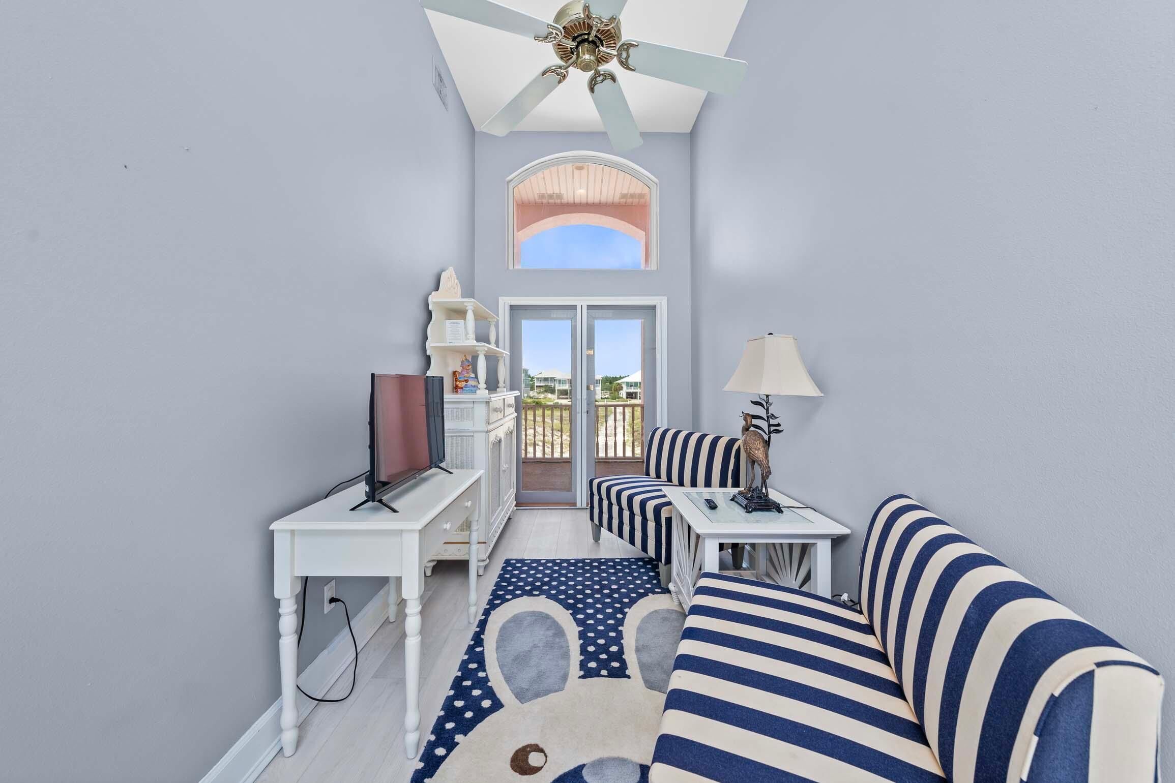 A compact living space with a ceiling fan, a sofa, a TV, and a dining table.