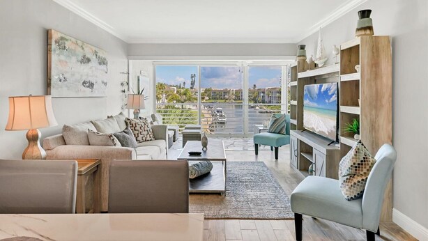 A modern living room with a sofa, armchairs, a coffee table, and a TV on a wooden stand. - 2/2 Canal front condo, Pool, Beach Access (Longboat Key)