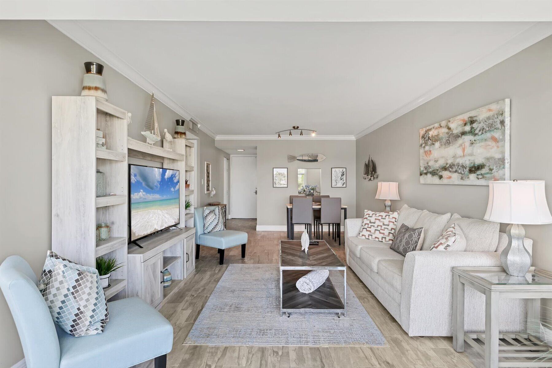 A living room with a TV, a sofa, a coffee table, and a dining area with chairs and a table.