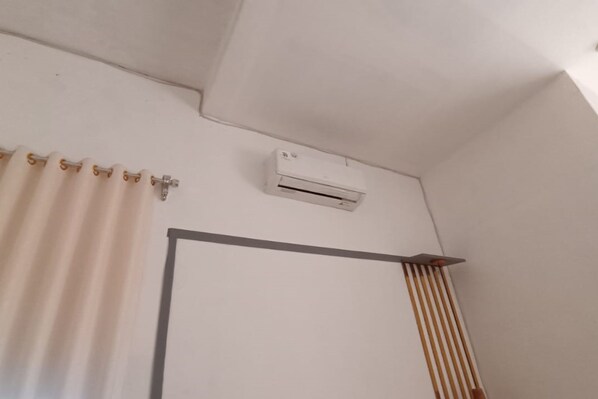 A room with a white ceiling, a white air conditioning unit mounted on the wall, and a white door with a black frame. - Hotel O Seven Secrets Syariah (Ngaglik)