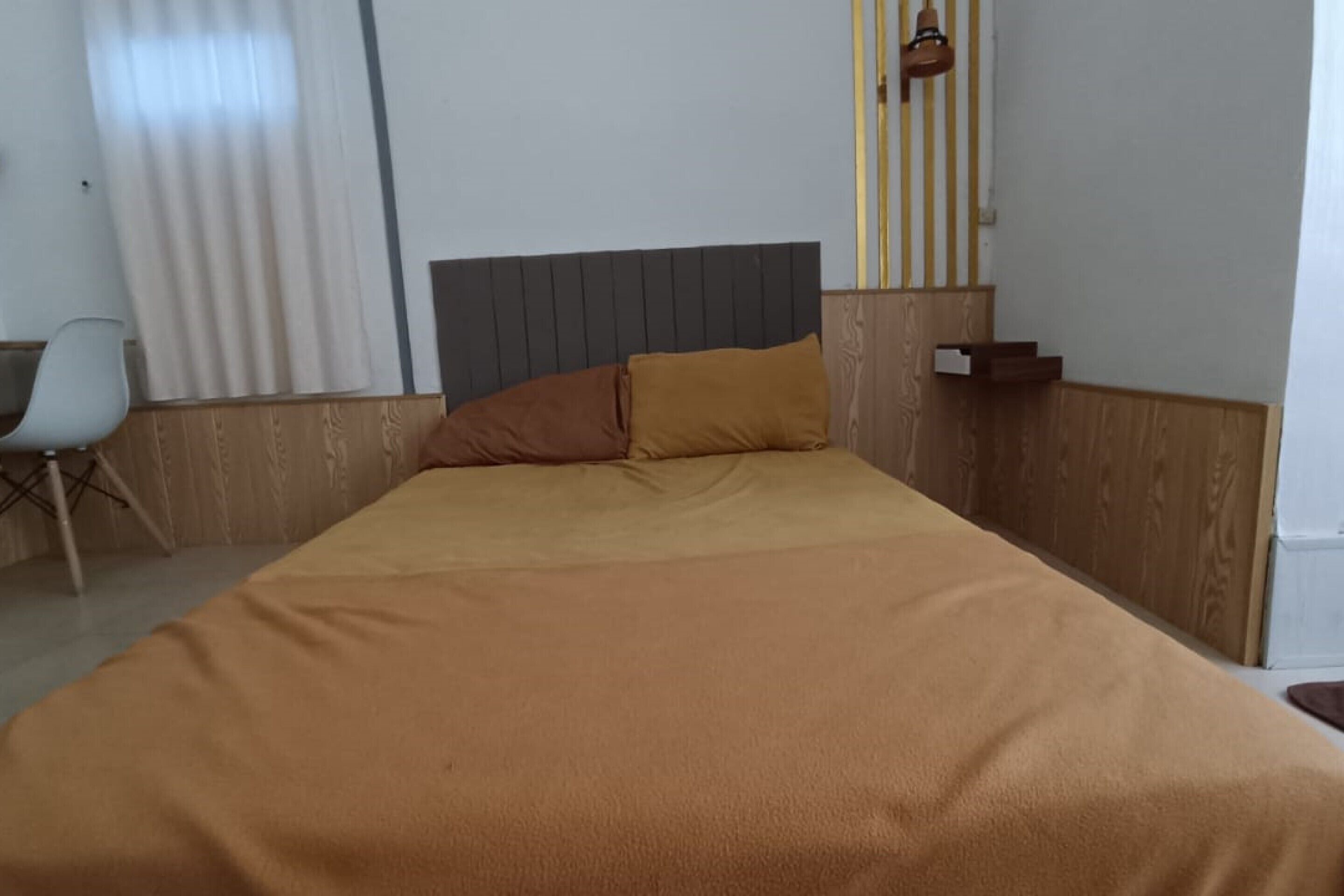 A single bed with a brown headboard and a matching brown blanket.