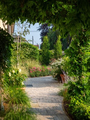 A paved pathway surrounded by lush greenery and flowering plants.
