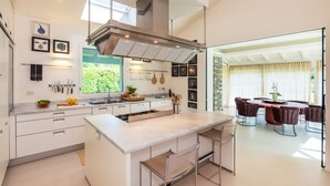 A modern kitchen with a central island, bar stools, and a dining area with a table and chairs.