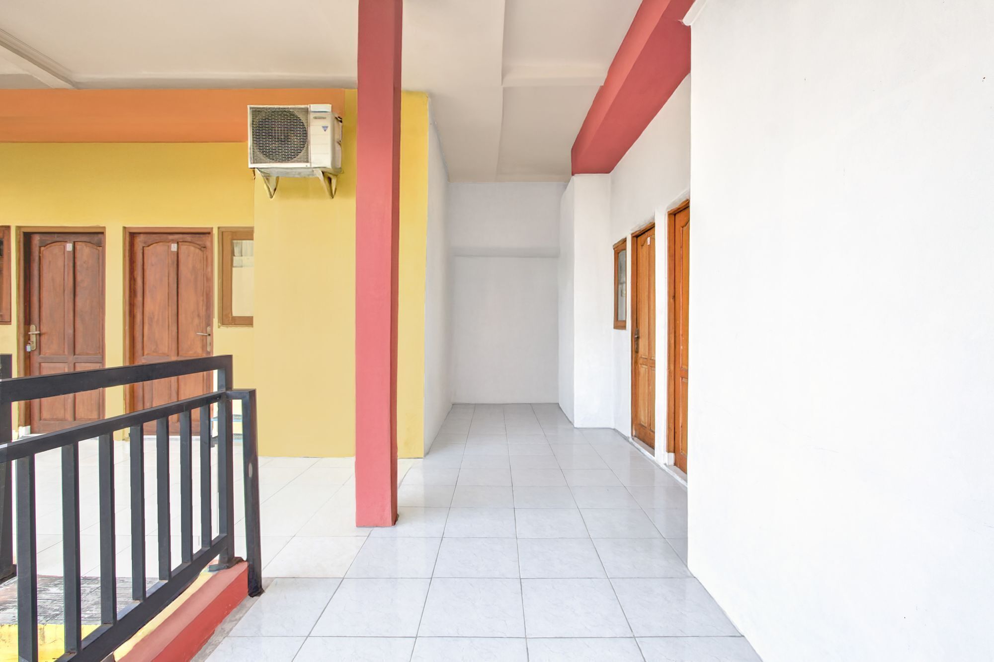 A hallway with a tiled floor, a red pillar, and a ceiling-mounted air conditioning unit.
