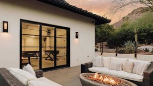 A patio area with a fire pit, outdoor furniture, and a sliding glass door leading to an interior space.