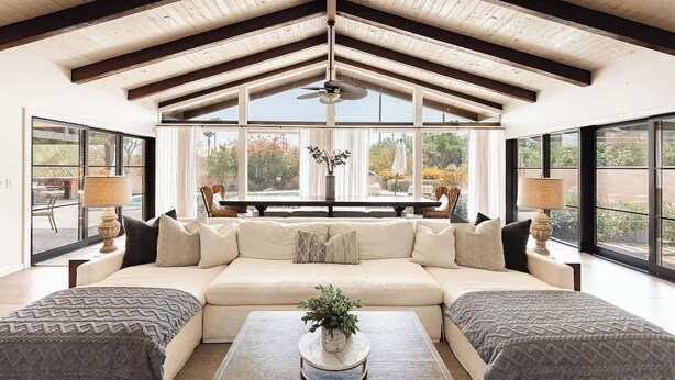 A spacious living room with a high ceiling, large windows, a sofa, and a coffee table.