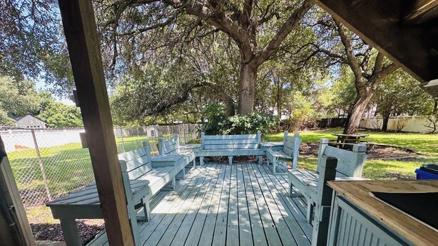 A wooden deck with benches and a picnic table, surrounded by trees and a fenced yard. - Boat & pet friendly. Minutes to Emerald Isle & a half mile to the boat ramp. (Cedar Point)