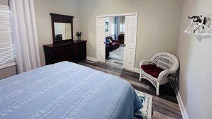 A bedroom with a bed, dresser, mirror, and a white chair. - Boat & pet friendly. Minutes to Emerald Isle & a half mile to the boat ramp. (Cedar Point)