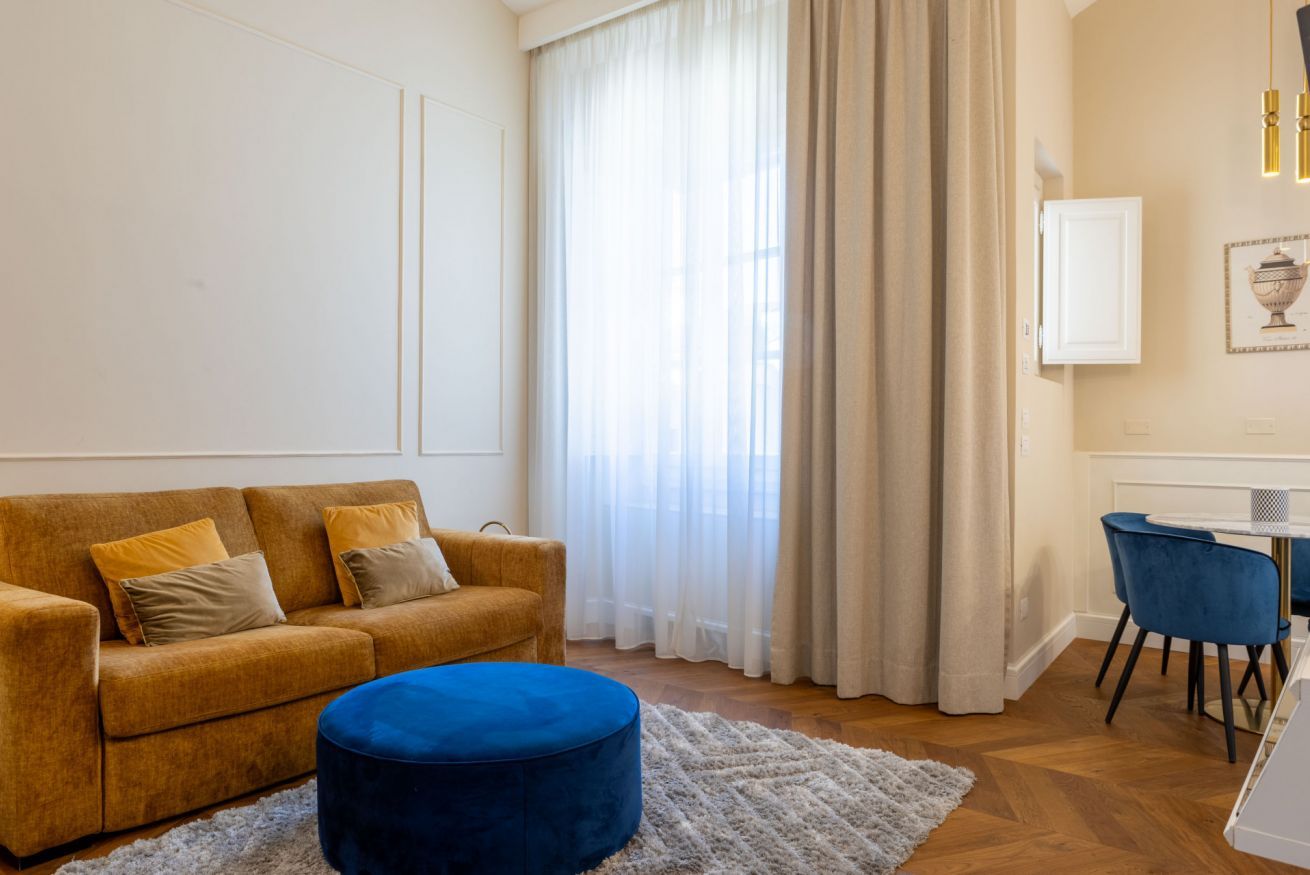 A living room with a sofa, ottoman, and a dining area with chairs and a table.