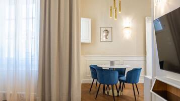 Un'area pranzo moderna con un tavolo rotondo e sedie blu, una TV a destra e un quadro appeso al muro.