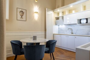 A modern kitchen with white cabinets, a marble countertop, and a built-in microwave.