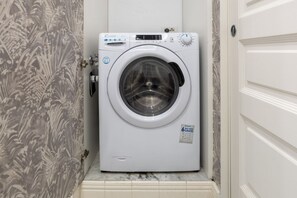 A front-loading washing machine in a bathroom with a marble countertop and a door with a handle. - Calzaiuoli Gold Private House with Terrace (Firenze)