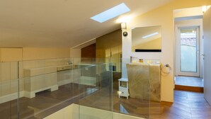 A spacious living area with a glass railing, a skylight, and a modern bathroom with a marble countertop. - Calzaiuoli Gold Private House with Terrace (Firenze)